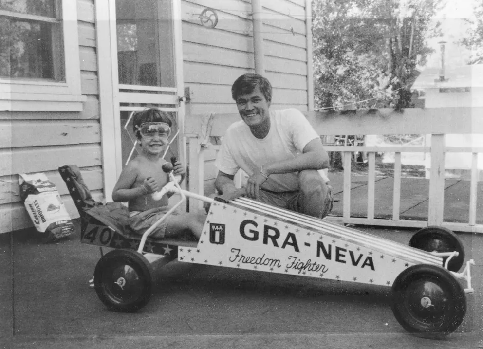 Brendan Brooks in the seat of a modified race go-kart with Wally Brooks next to him.